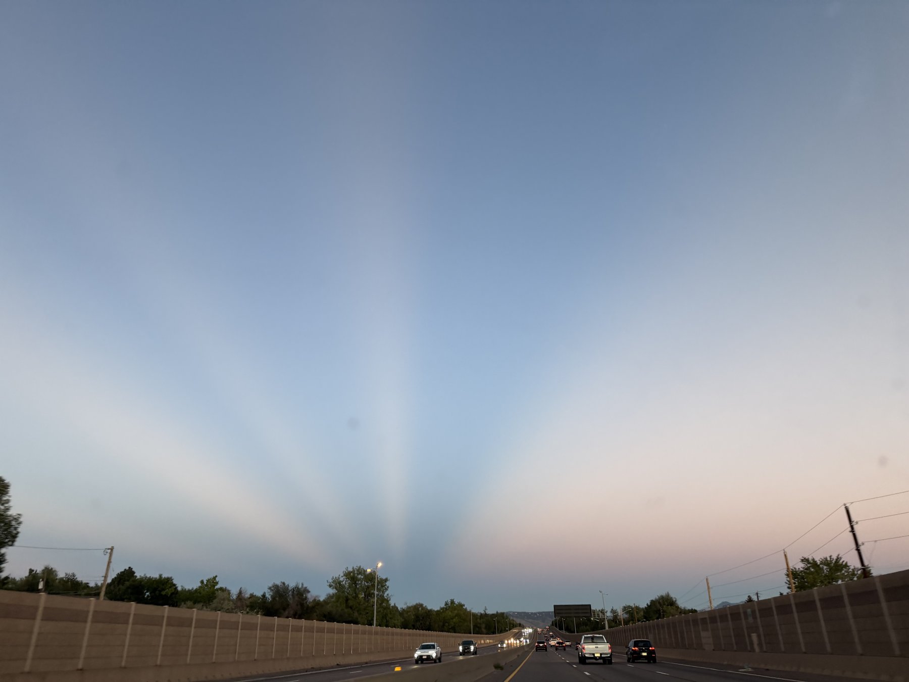 Evening light fanning across the sky above an open road