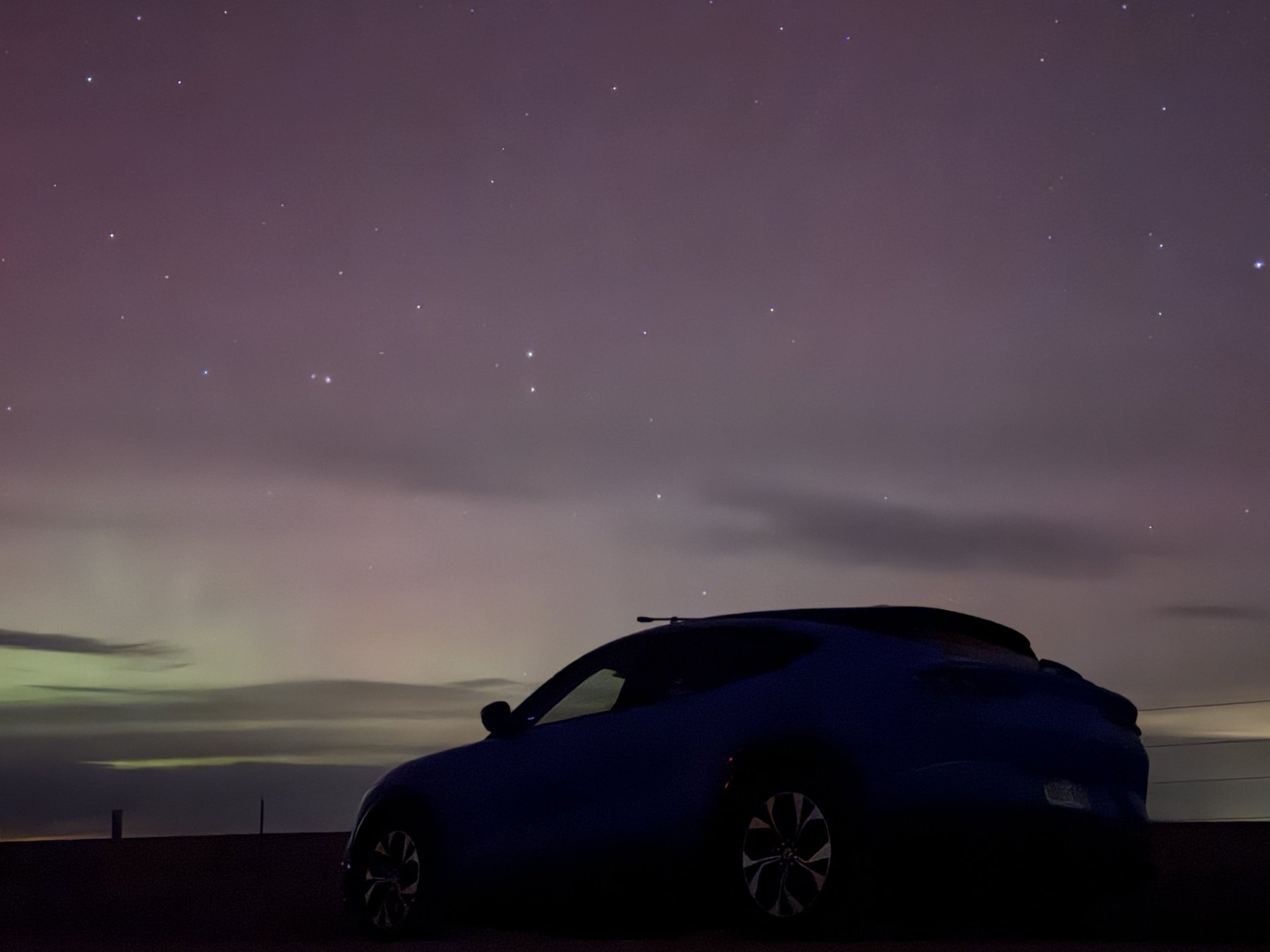 A blue car beneath the northern lights